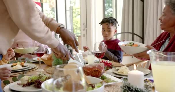 アフリカ系アメリカ人の父親は 多世代の家族のクリスマスディナーテーブルで肉を彫っています クリスマス お祝い トータルネスと家庭生活 変わらない — ストック動画