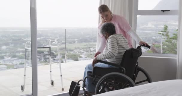 Χαμογελαστή Λευκή Νοσοκόμα Μια Ηλικιωμένη Αφροαμερικανή Ασθενή Αναπηρική Καρέκλα Αργή — Αρχείο Βίντεο