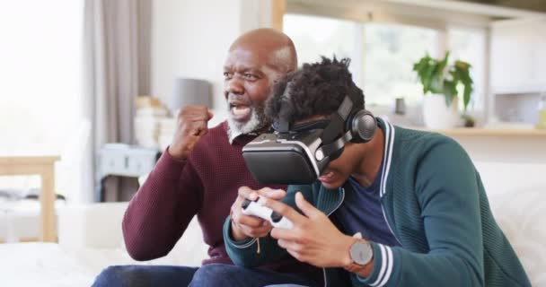 Χαρούμενος Αφροαμερικάνος Γιος Που Χρησιμοποιεί Ακουστικά Και Gamepad Τον Πατέρα — Αρχείο Βίντεο