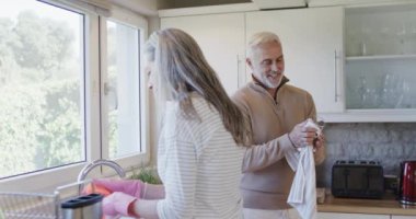 Orta yaşlı beyaz çift mutfakta fotokopi odasıyla yıkanıyor. Yıkama, temizlik, ilişkiler, ev hayatı ve yaşam tarzı konsepti, değiştirilmemiş.