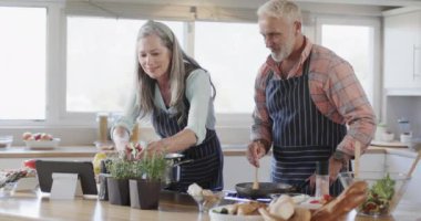 Orta yaşlı beyaz çift yemek hazırlıyor, evde birlikte yemek pişiriyorlar, ağır çekimde. İlişki, yemek, yemek, yaşam tarzı ve ev hayatı, kopyalama alanı, değiştirilmemiş.