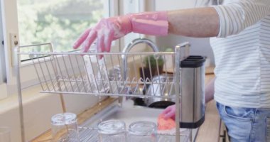 Orta yaşlı beyaz kadın elleri fotokopi odasıyla mutfakta eldiven yıkıyor. Yıkama, temizlik, ev hayatı ve yaşam tarzı konsepti, değiştirilmemiş..