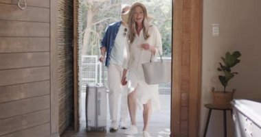 Mutlu orta yaşlı beyaz doğada otel odasına geliyor, ağır çekimde. İlişki, seyahat, kaçış, yaşam tarzı ve rahatlama konsepti, kopyalama alanı, değiştirilmemiş.