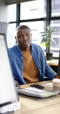 Ofiste çalışan Afrikalı Amerikalı iş adamının dikey videosu, yavaş çekim, kopyalama alanı. İş, ofis, iş, profesyonel konsept, değiştirilmemiş.