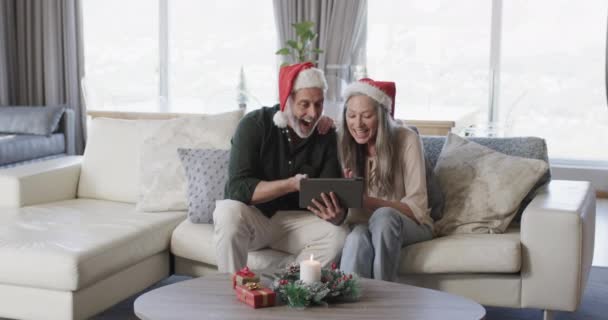 中年夫妇戴着圣诞礼帽在家中的平板视频聊天 动作缓慢 圣诞节 庆祝活动 生活方式和家庭生活 复制空间 — 图库视频影像