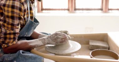 Çömlek atölyesinde çömlekçi çarkını kullanan Afrikalı Amerikalı erkek çömlekçi, yavaş çekim. Çömlek, seramik, el yapımı, yerel işletme, hobiler ve el işi, değiştirilmemiş.