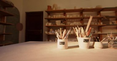 Çömlek atölyesindeki masadaki fırçalar ve çömlek aletleri. Çömlek, seramik, el yapımı, yerel işletme, hobiler ve zanaat.