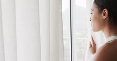 Evde pencereden bakan mutlu melez kadın, ağır çekimde. Yaşam tarzı ve ev hayatı, değişmedi..