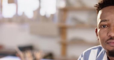 Sakallı, çömlek atölyesinde oturup gülümseyen Afro-Amerikan bir adamın yarım yüzü. Çömlek, seramik, el yapımı, yerel işletme, hobiler ve el işi, değiştirilmemiş.