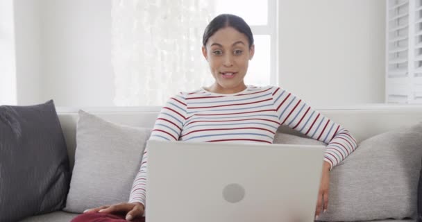 ハッピーな女性は ビデオ通話のためのラップトップを使用してソファに座っています スローモーション ライフスタイル コミュニケーション 家庭生活 変わらない — ストック動画
