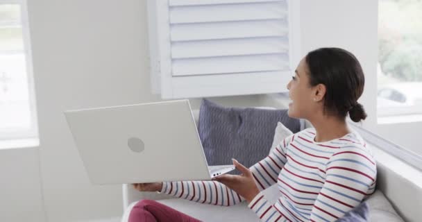 ハッピーな女性は ビデオ通話のためのラップトップを使用してソファに座っています スローモーション ライフスタイル コミュニケーション 家庭生活 変わらない — ストック動画