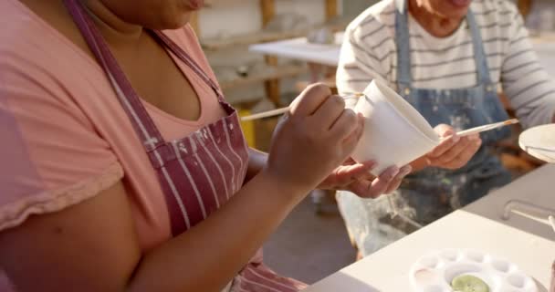 两个不同的女陶工在陶艺工作室里给陶瓷壶上光 微笑着 动作缓慢 手工制品 当地企业 业余爱好和工艺 未经改动 — 图库视频影像