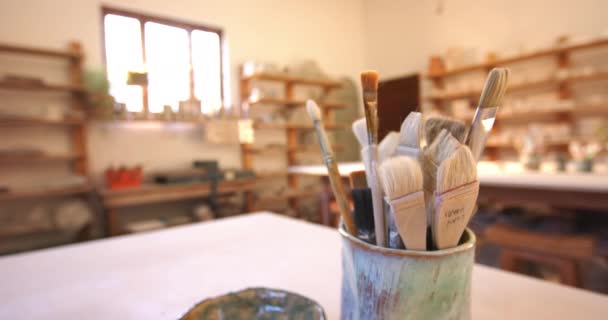 陶芸スタジオで机の上にブラシや陶器の道具 手作り 地元のビジネス 趣味および工芸品 — ストック動画