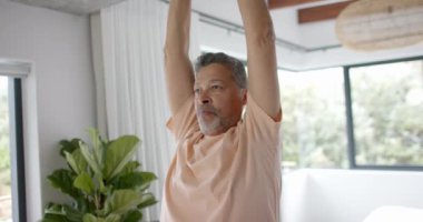 Evde yoga yapan kıdemli melez adam. Emeklilik, dinlenme, egzersiz ve sağlıklı yaşam tarzı konsepti, değişmedi..