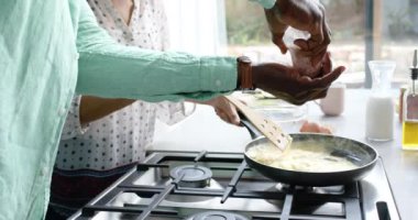 Çift ırklı çift mutfakta yemek pişiriyor ve tavada baharatlı omlet yapıyor, ağır çekimde. Ev hayatı, yemek ve yaşam tarzı, değişmemiş..