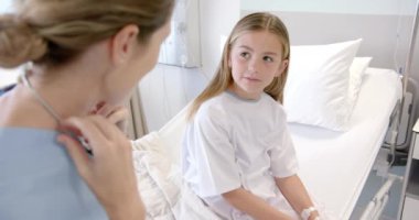 Kafkasyalı kadın doktor hastane yatağında steteskop kullanıyor, ağır çekimde. Kontrol, çocukluk, hastalık, sağlık hizmetleri, sağlık ve hastane, değiştirilmemiş.