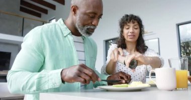 Çift ırklı mutlu çift kahvaltı yapıyor ve baharatlı yumurtaları mutfakta pişiriyor, ağır çekimde. Ev hayatı, yemek ve yaşam tarzı, değişmemiş..