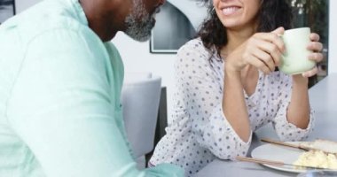 Çift ırklı mutlu çift kahvaltıda omlet yiyor ve mutfakta konuşuyor, ağır çekimde. Ev hayatı, yemek ve yaşam tarzı, değişmemiş..