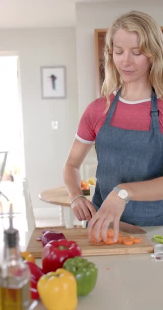 キッチンで野菜を切るハッピーな白人女性の肖像画の垂直ビデオ ゆっくりとした動き 家庭生活 ライフスタイル 変わらない — ストック動画