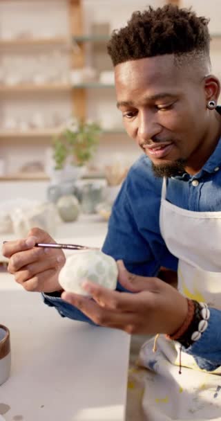 快乐的非洲裔美国陶工在陶瓷工作室里给陶瓷壶上光 动作缓慢 手工制品 当地企业 业余爱好和工艺 未经改动 — 图库视频影像