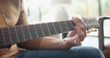 Evdeki güneşli odada gitar çalan kıdemli çift ırklı adamın orta bölümü, yavaş çekim. Müzik, rahatlama, yaratıcılık, hobiler, emeklilik, ev hayatı ve yaşlılar yaşam tarzı, değiştirilmemiş.