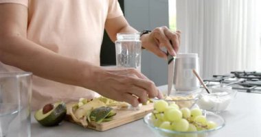 Üst düzey melez bir adamın evde sağlıklı bir içecek hazırlaması, ağır çekimde. Emeklilik, refah, beslenme, yemek ve sağlıklı yaşam tarzı, değişmemiş..