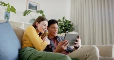 Kanepede oturup tablet kullanan mutlu çift, ağır çekimde. İlişki, birliktelik, iletişim, yaşam tarzı ve aile hayatı, değişmedi..