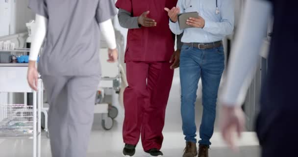 Zróżnicowani Lekarze Omawiający Pracę Pomocą Tabletu Spacerującego Korytarzu Szpitalnym Zwolniony — Wideo stockowe