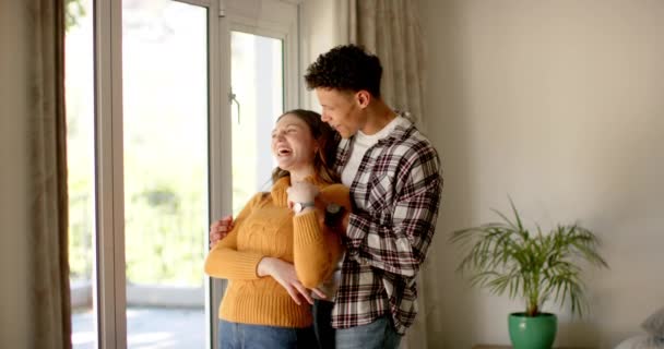 Szczęśliwa Zróżnicowana Para Patrząca Przez Okno Obejmująca Się Domu Zwolnionym — Wideo stockowe