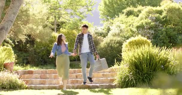 ハッピー多様なカップルが手を握り 晴れた庭でゆっくりと歩いています 関係性 トータル性 ライフスタイル 夏と自然 変わらない — ストック動画