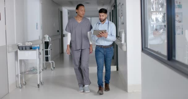 Monipuoliset Mies Naislääkärit Keskustelevat Työstä Tabletin Avulla Sairaalan Käytävällä Hidastettuna — kuvapankkivideo