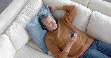 Kulaklıklı koltukta oturan, akıllı telefondan müzik dinleyen, fotokopi çeken, ağır çekim kıdemli bir melez. Müzik, rahatlama, iletişim, emeklilik, ev hayatı ve yaşlılar yaşam tarzı, değişmemiş.