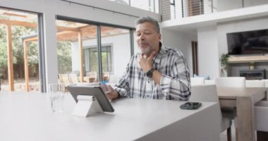 İlaçlı kıdemli melez adam, doktorla videolu görüşme yapıyor, yavaş çekim. Teletıp, sağlık hizmetleri, tıbbi danışma, iletişim, ev hayatı ve yaşlılar yaşam tarzı, değiştirilmemiş.