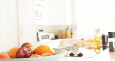 Güneşli mutfakta meyveler kasede ve baharatlar tezgahta, yavaş çekimde. Ev, yemek, sağlık, meyve.