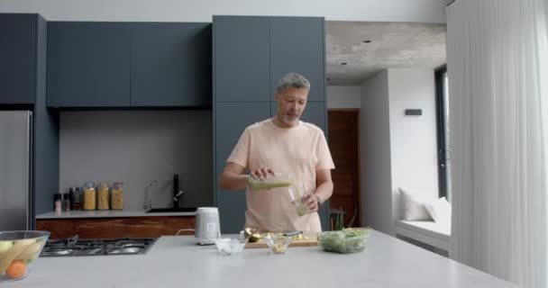 Feliz Hombre Biracial Senior Vertiendo Batido Saludable Vidrio Cocina Casa — Vídeo de stock