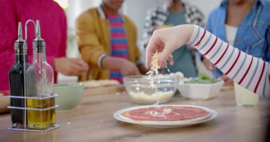 Mutfakta yemek pişiren ve pizza yapan çeşitli genç arkadaşlar grubu, yavaş çekim. Gen z, arkadaşlık, takılma, yemek ve yaşam tarzı, değişmemiş.