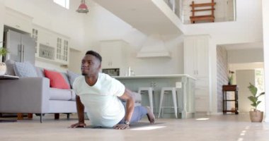 Odaklanmış Afro-Amerikan adam güneşli oturma odasında şınav çekiyor, ağır çekimde. Ev, egzersiz, fitness ve sağlıklı yaşam tarzı, değişmemiş..