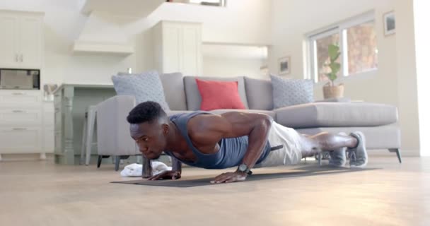 专注的非洲裔美国人在阳光灿烂的客厅里做俯卧撑 动作缓慢 健身和健康的生活方式 — 图库视频影像