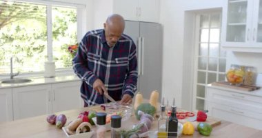 Kıdemli Afro-Amerikan adam mutfakta sebze doğruyor, fotokopi çekiyor, yavaş çekimde. Ev hayatı, emeklilik, yemek ve sağlıklı yaşam tarzı, değişmemiş..