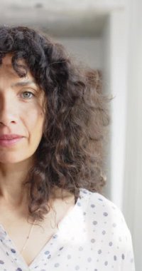 Kıvırcık saçlı, gülümseyen, ağır çekimde olgun, beyaz bir kadının dikey portresi. Mutluluk, ev hayatı ve yaşam tarzı, değişmedi..