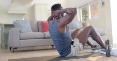 Odaklanmış Afro-Amerikan adam güneşli oturma odasında mekik çekiyor, ağır çekimde. Ev, egzersiz, fitness ve sağlıklı yaşam tarzı, değişmemiş..