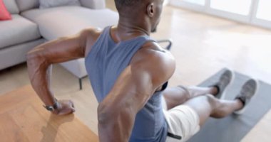 Odaklanmış Afro-Amerikalı adam güneşli oturma odasında şınav çekiyor, ağır çekimde. Ev, egzersiz, fitness ve sağlıklı yaşam tarzı, değişmemiş..
