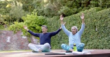 Bahçede yoga meditasyonu yapan farklı yaşlı çiftler. Emeklilik, boş zaman, sağlıklı yaşam tarzı, birliktelik ve doğa konsepti, değişmemiş..