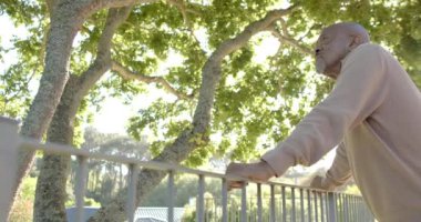 Düşünceli kıdemli çift ırklı adam evdeki balkona hayran, ağır çekimde. Ev hayatı, emeklilik, doğa ve yaşam tarzı, değişmemiş..