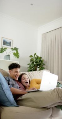 Kanepede oturan mutlu çiftin evdeki laptoplarını yavaş çekimde kullandıkları dikey video. İlişki, birliktelik, iletişim, yaşam tarzı ve aile hayatı, değişmedi..
