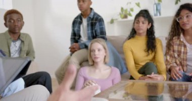 Düşünceli bir grup genç arkadaş tablet kullanıyor ve evde konuşuyorlar, ağır çekimde. Gen Z, arkadaşlık, takılma, teknoloji, terapi ve yaşam tarzı, değiştirilmemiş.