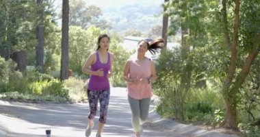 Güneşli bir günde ormanın yakınında koşan Asyalı mutlu bayan arkadaşlar, ağır çekimde. Yaz, egzersiz, fitness, sağlıklı yaşam tarzı, doğa, arkadaşlık, değişmemiş.