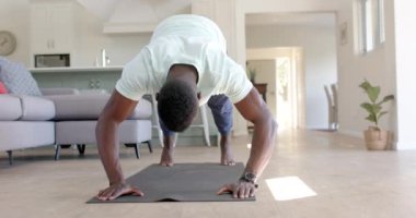 Odaklanmış Afro-Amerikan adam güneşli oturma odasında şınav çekiyor, ağır çekimde. Ev, egzersiz, fitness ve sağlıklı yaşam tarzı, değişmemiş..