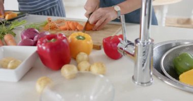 Önlük giyen ve tabletle yemek yapan farklı çiftler, ağır çekimde. Ev hayatı, teknoloji, yemek ve yaşam tarzı, değişmedi..