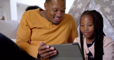 Mutlu Afro-Amerikan babası ve kızı çadırda tablet kullanıyor, ağır çekimde. Aile hayatı, aile, teknoloji ve yaşam tarzı, değişmedi..